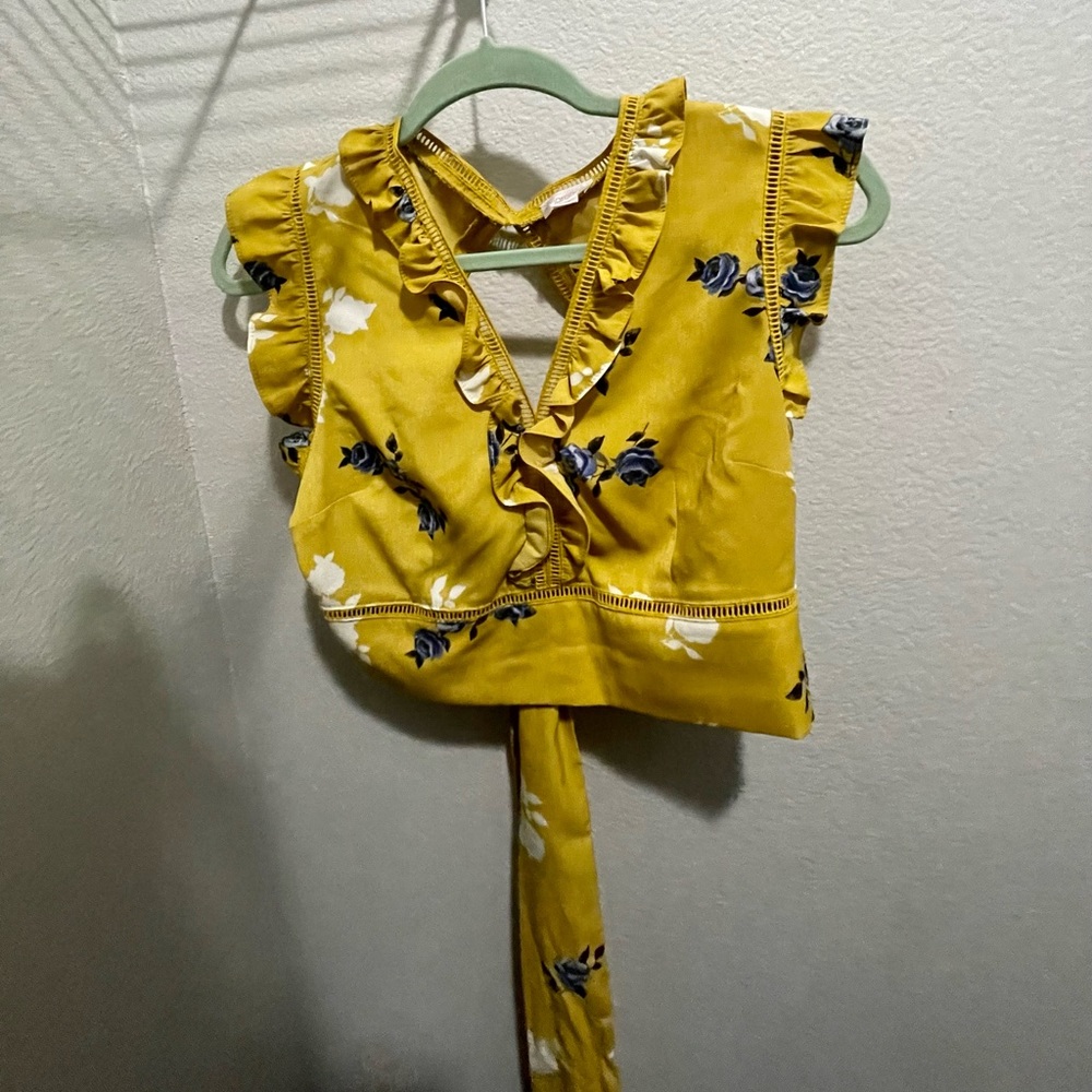 A yellow crop top blouse that has blue floral flowers throughout.